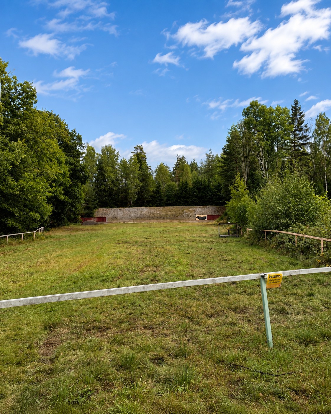 Älgbanan med löparställ, varningsskylt och kulfångsvall i bakgrunden.